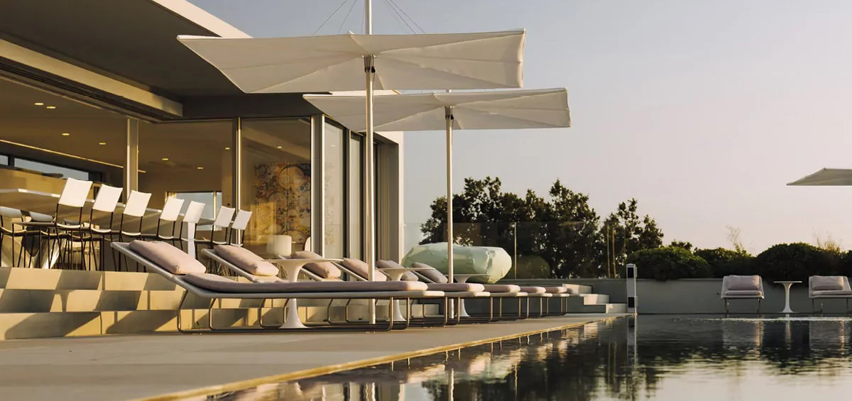 Umbrosa Sonnenschirm an einem Wasserbecken beschatten Liegestühle.