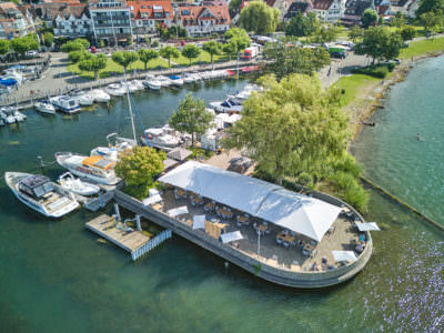 Weiße Zeltsonnenschirme an einem Hafen mit mehreren kleinen Sonnenschirmen ergänzt.