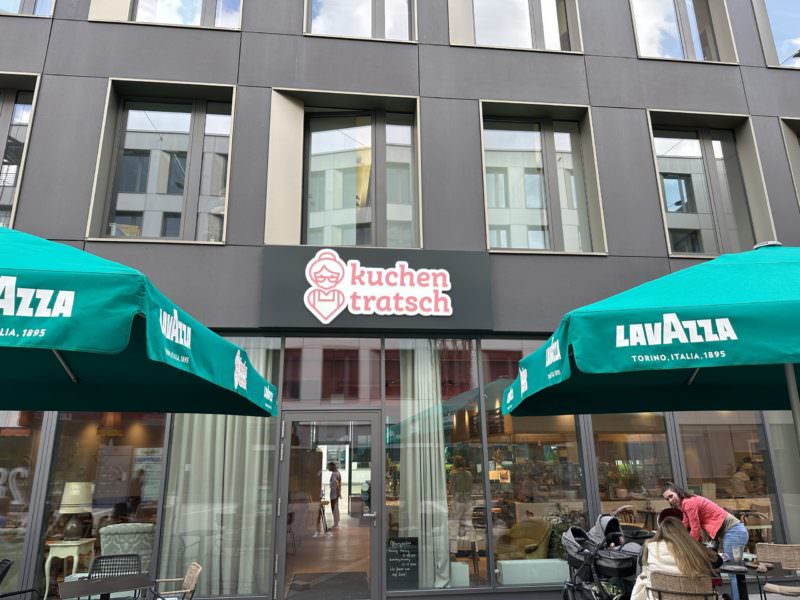 Das Kuchentratsch in München mit grünen Sonnenschirmen.