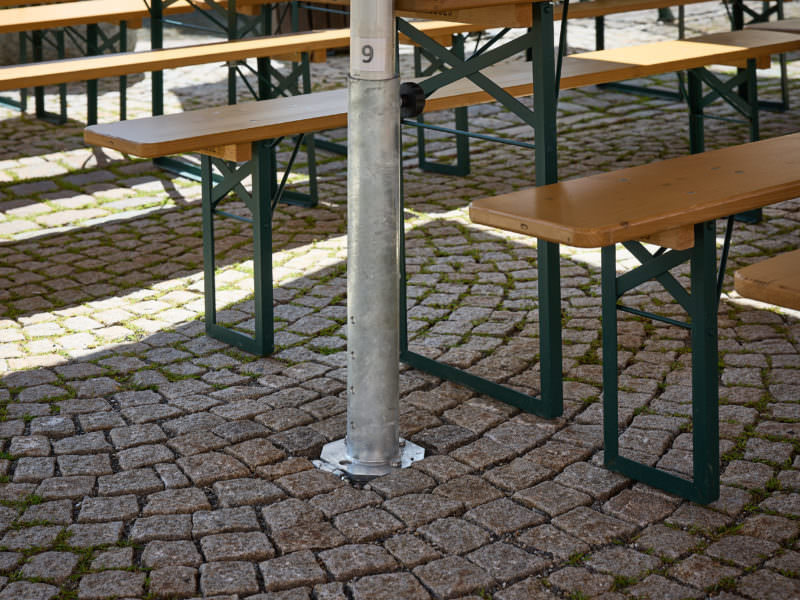 Eine Bodenhülse, und Bierbänke und Tische im Hintergrund.