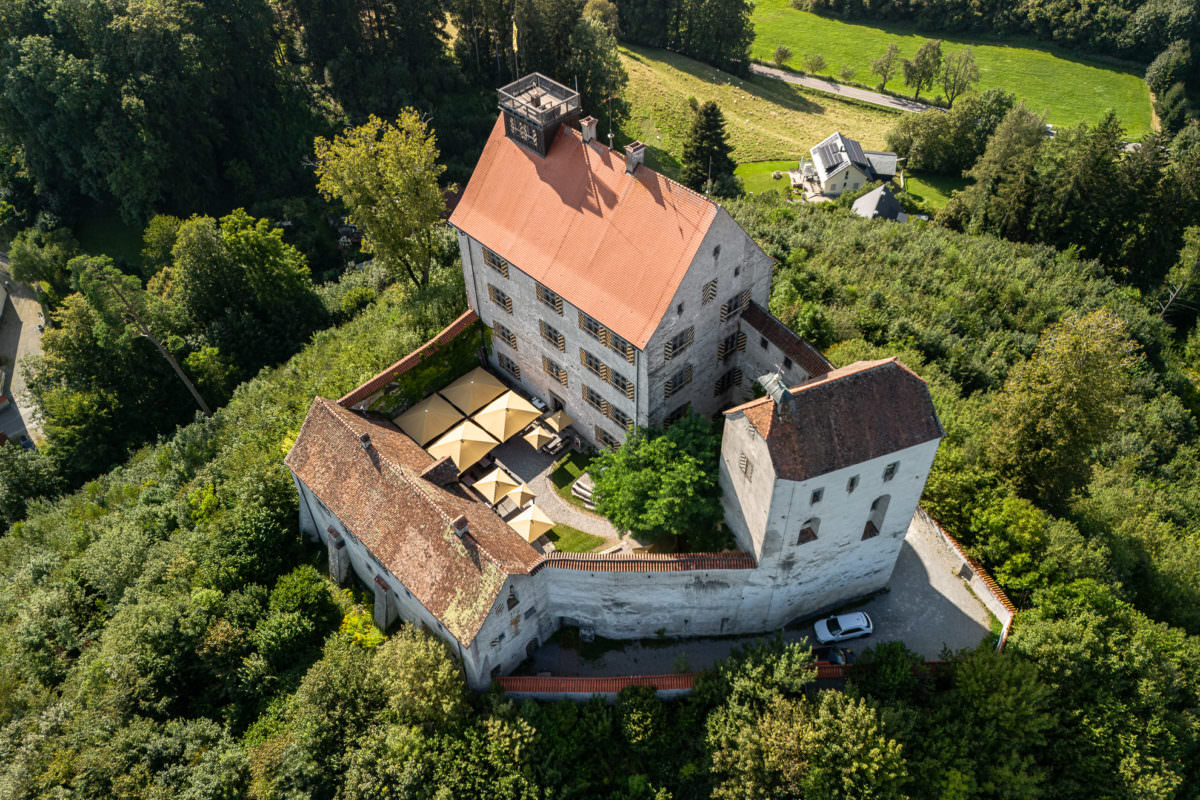 Waldburg mit gelben Sonnenschirmen auf einem Hügel.